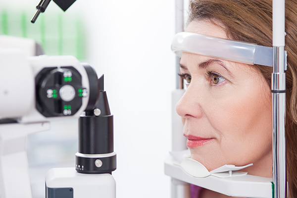 Cheerful woman is having eye examination at the slit lamp in optometrist lap